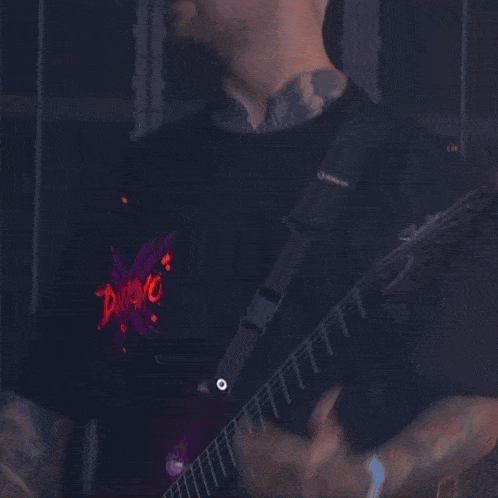 a man is playing a guitar and wearing a shirt that says ' slayer ' on it