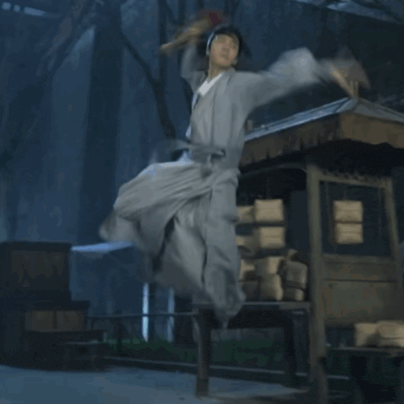a man in a white dress is running in front of a wooden hut