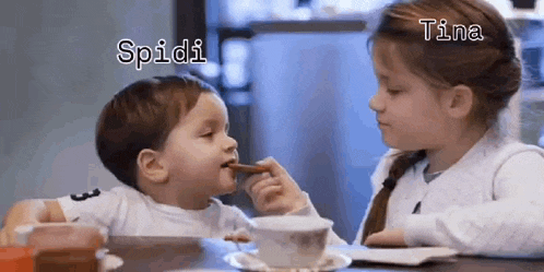 a little boy and a little girl are sitting at a table eating food .