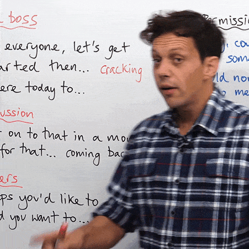 a man in a plaid shirt stands in front of a whiteboard that says " boss " on it
