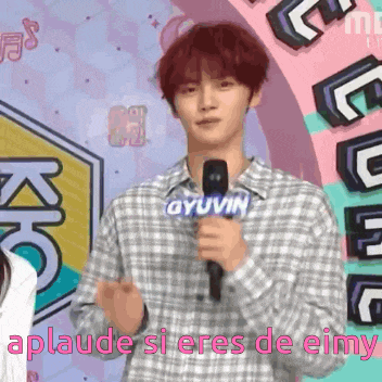 a man in a plaid shirt is holding a microphone and says aplaude si eres de eimy on the bottom
