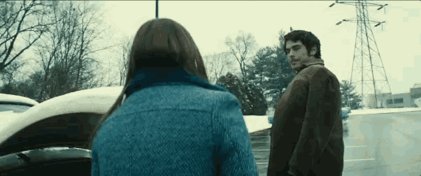 a man and a woman are standing next to each other in a parking lot