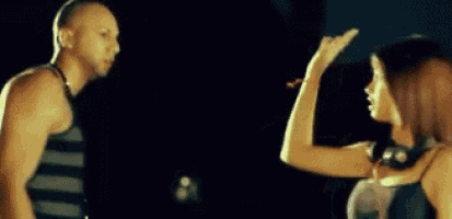 a man and a woman are standing next to each other and the woman is pointing at the man 's head .