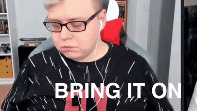 a man wearing glasses and headphones is sitting in front of a screen that says bring it on