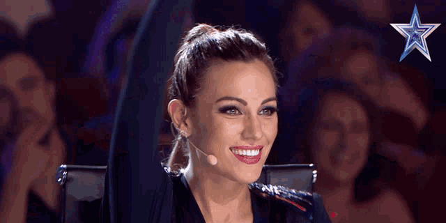 a woman is smiling in front of a microphone with a blue star in the background