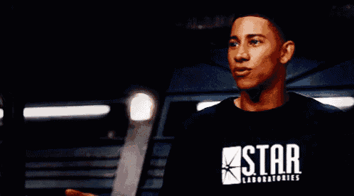 a man wearing a black star laboratories shirt stands in a dark room