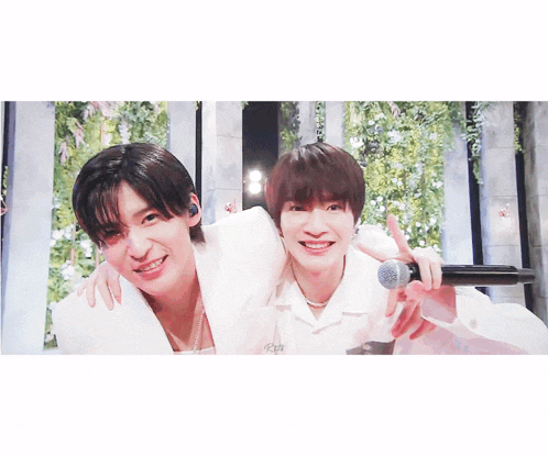 two young men are posing for a picture with a microphone and smiling