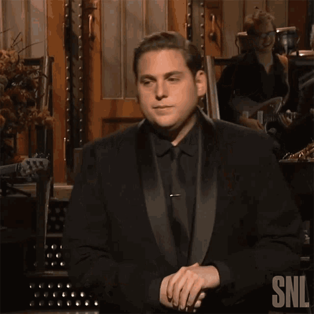 a man in a tuxedo with snl written on the bottom