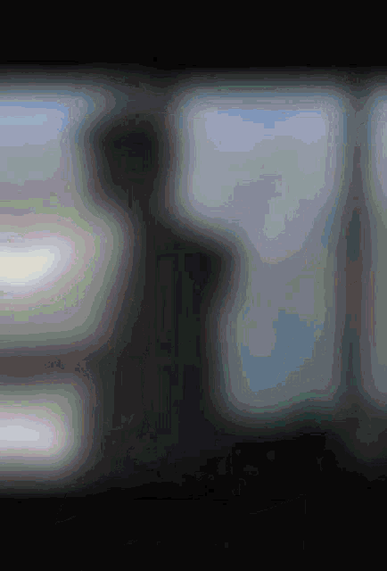 a blurred image of a person standing in front of a window with the number 3 in the corner