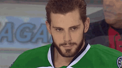a man with a beard is wearing a green jersey that says dallas on the front