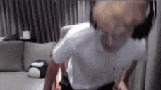 a man in a white shirt is standing in front of a couch .