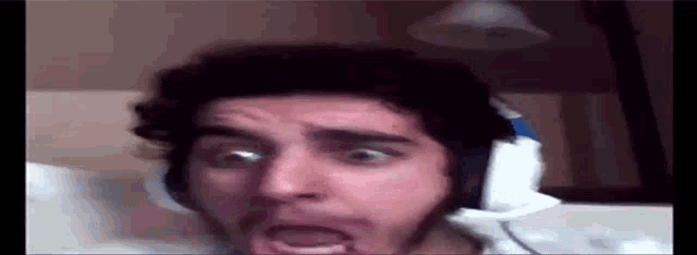 a man wearing headphones is making a funny face while sitting on a bed .