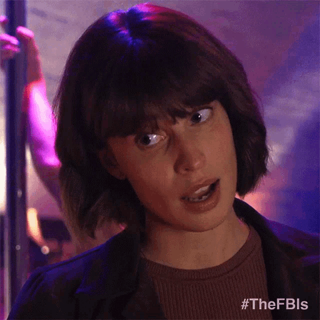 a woman with short hair and bangs is making a funny face in a dark room .