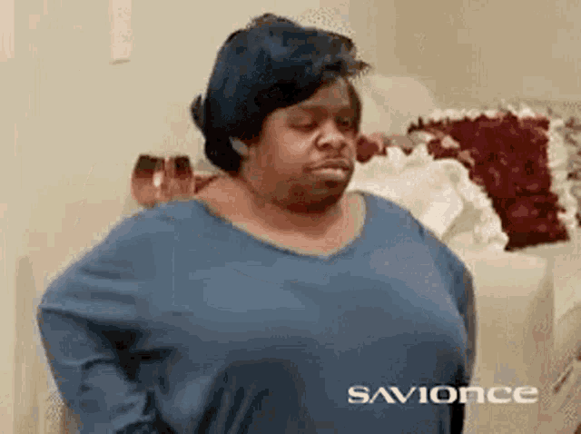 a woman in a blue shirt is standing in front of a couch .