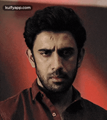 a close up of a man 's face with a beard and a red shirt .