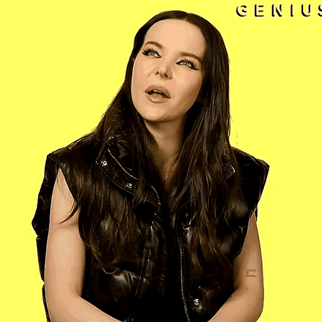 a woman wearing a black vest with the word genius on the yellow background
