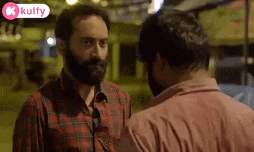 a man with a beard is talking to another man in a red plaid shirt .