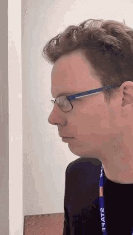 a man wearing glasses has a lanyard that says fat2