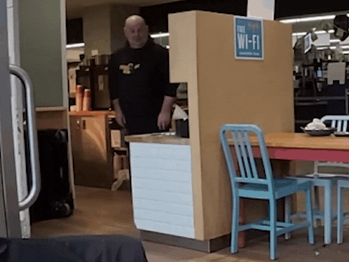 a man in a black shirt stands in front of a free wi-fi sign