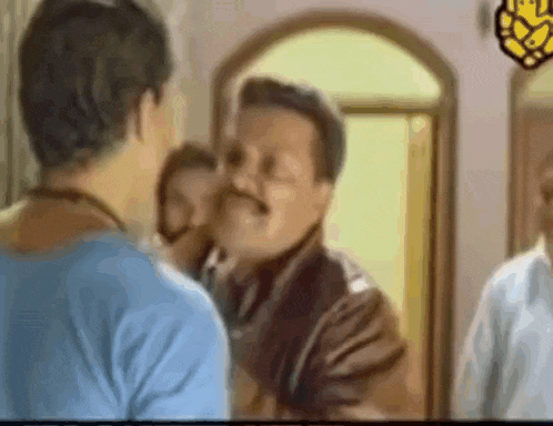 a man with a mustache is standing in front of a mirror talking to another man .