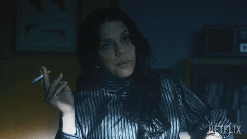 a woman in a striped shirt is smoking a cigarette with a netflix logo in the corner