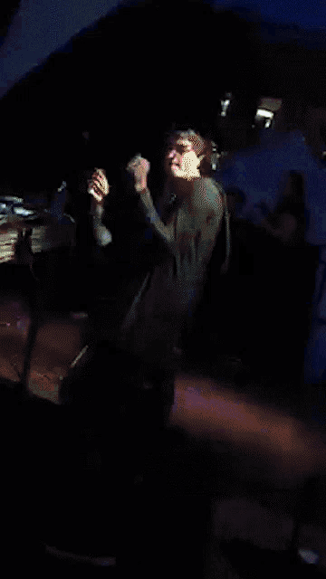 a man in a blue shirt is playing a guitar on a stage