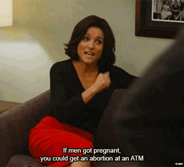 a woman sitting on a couch talking to a man and says if men got pregnant you could get an abortion
