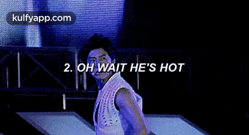a man is dancing on a stage with the words `` oh wait he 's hot '' behind him .