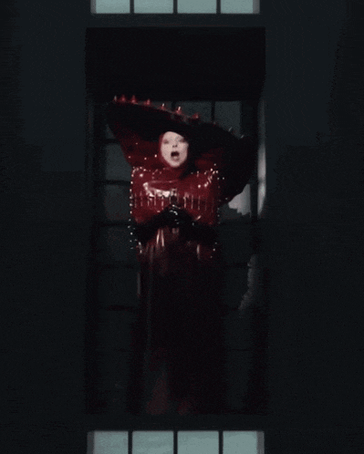 a woman in a red costume is standing in a window