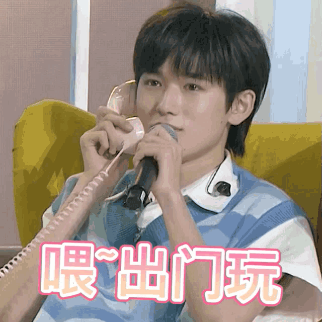 a young man is holding a microphone while talking on a telephone with chinese writing behind him