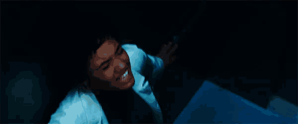 a man in a white shirt and tie is laying on the floor in the dark .
