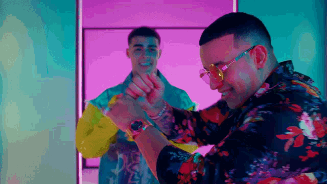 a man in a floral shirt and sunglasses looks at his watch