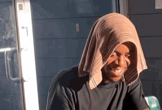 a man with a towel covering his head is smiling