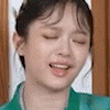 a close up of a woman 's face with her eyes closed wearing a green jacket .