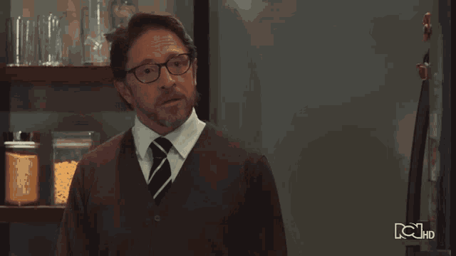 a man wearing glasses and a tie is standing in front of a tv screen that says ' rc hd ' on it
