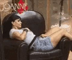 a woman is laying in a chair with her legs crossed and looking at the camera .