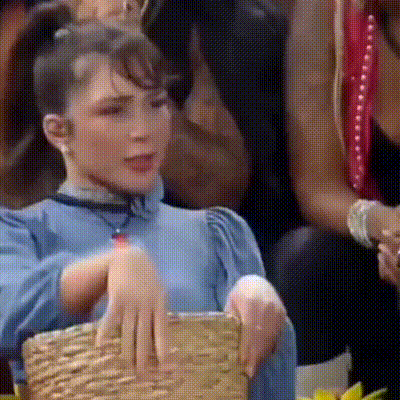 a woman in a blue dress is holding a wicker basket in her hands .