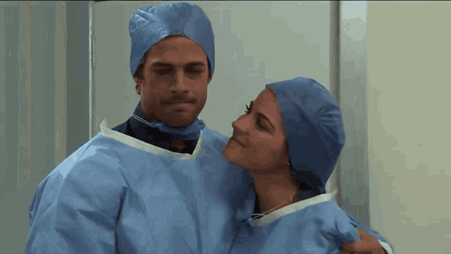 a man and a woman wearing surgical gowns are hugging