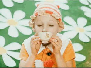 a little girl is drinking a cup of tea