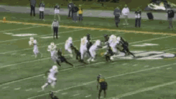 a group of football players are running on a field with a referee .