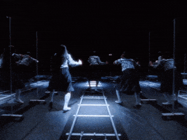 a group of people are dancing in a dark room with a ladder in the middle