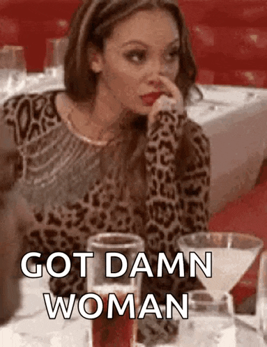 a woman in a leopard print sweater is sitting at a table with a martini glass and a glass of wine .