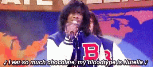 a man is singing into a microphone with the letter b on his jacket .