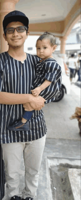 a man in a striped shirt is holding a child