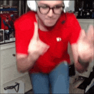 a man in a red shirt and glasses is giving a thumbs up
