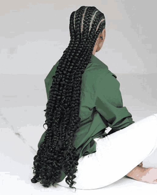 a woman wearing a green shirt and white pants has long braids