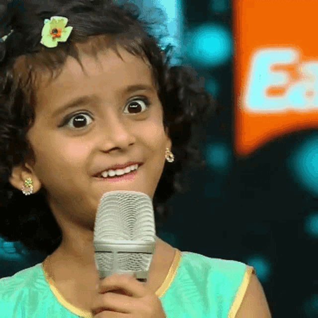 a little girl is holding a microphone and smiling