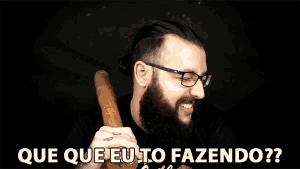 a man with a beard and glasses is holding a wooden object in his hand and covering his eyes with his hand .