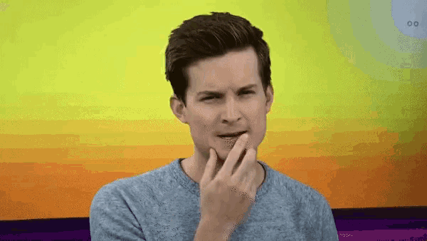 a man in a grey shirt is making a funny face with his hand on his chin