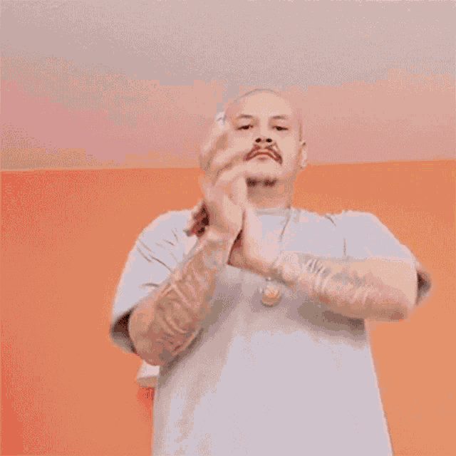 a man in a red shirt is clapping his hands in front of his face .
